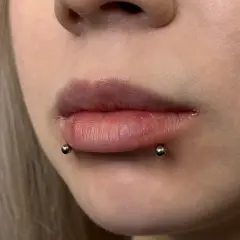 Usta z piercingiem snake bite. Dwa kolczyki z kulkami po bokach dolnej wargi, imitujące ukąszenie węża.