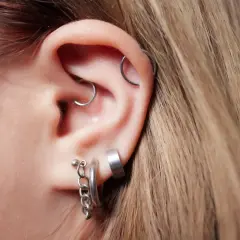 Ucho z kilkoma kolczykami, w tym modnym daith piercingiem.