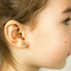 Małe, błękitne kolczyki w uchu dziewczynki, delikatny kolczyk dermal.