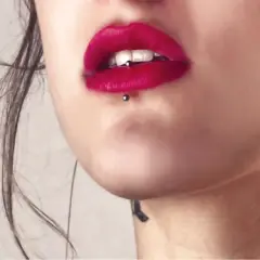 Usta z czerwoną szminką i ashley piercing. Delikatny tatuaż na szyi dodaje uroku.