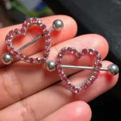 Dwa błyszczące kolczyki w kształcie serca z różowymi cyrkoniami, idealne na nipple piercing.