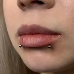 Usta z piercingiem snake bite. Dwa kolczyki z kulkami po bokach dolnej wargi, imitujące ukąszenie węża.