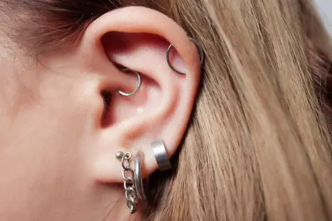 Ucho z kilkoma kolczykami, w tym modnym daith piercingiem.
