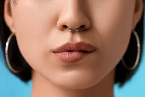 Kobieta z kolczykiem w nosie septum i kolczykami w uszach.