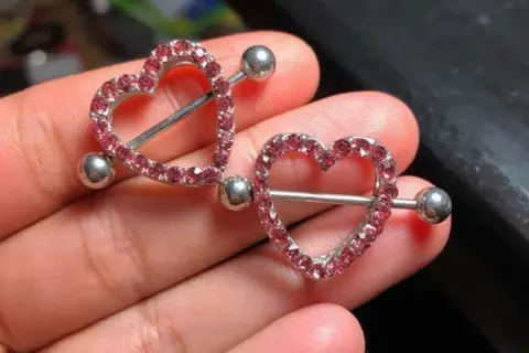 Dwa błyszczące kolczyki w kształcie serca z różowymi cyrkoniami, idealne na nipple piercing.