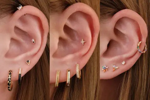 Ucho z kilkoma kolczykami, w tym z ozdobnym triple helix piercingiem i kolorowymi kamieniami.