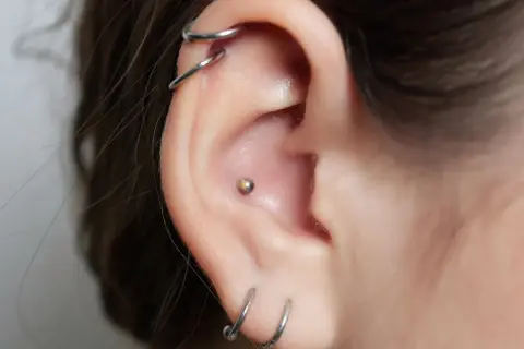 Ucho z kilkoma kolczykami, w tym vch piercing z małą kulką.