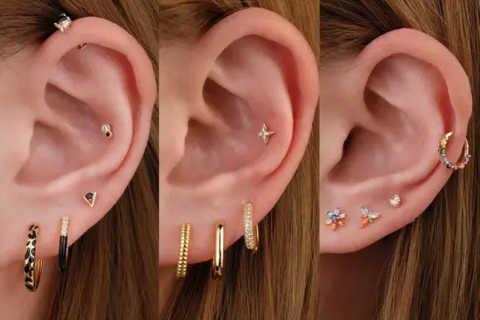 Ucho z kilkoma kolczykami, w tym z ozdobnym triple helix piercingiem i kolorowymi kamieniami.