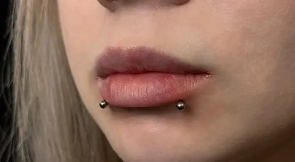 Usta z piercingiem snake bite. Dwa kolczyki z kulkami po bokach dolnej wargi, imitujące ukąszenie węża.