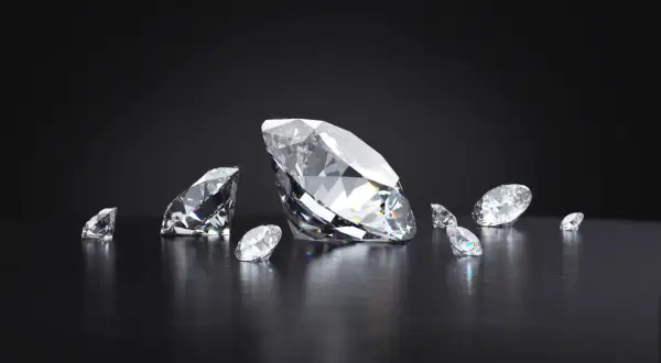 Kilka brylantów, w tym jeden duży, błyszczy na ciemnym tle. Każdy diament jest oszlifowany, by maksymalnie odbijać światło.