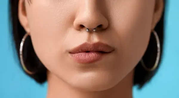 Kobieta z kolczykiem w nosie septum i kolczykami w uszach.