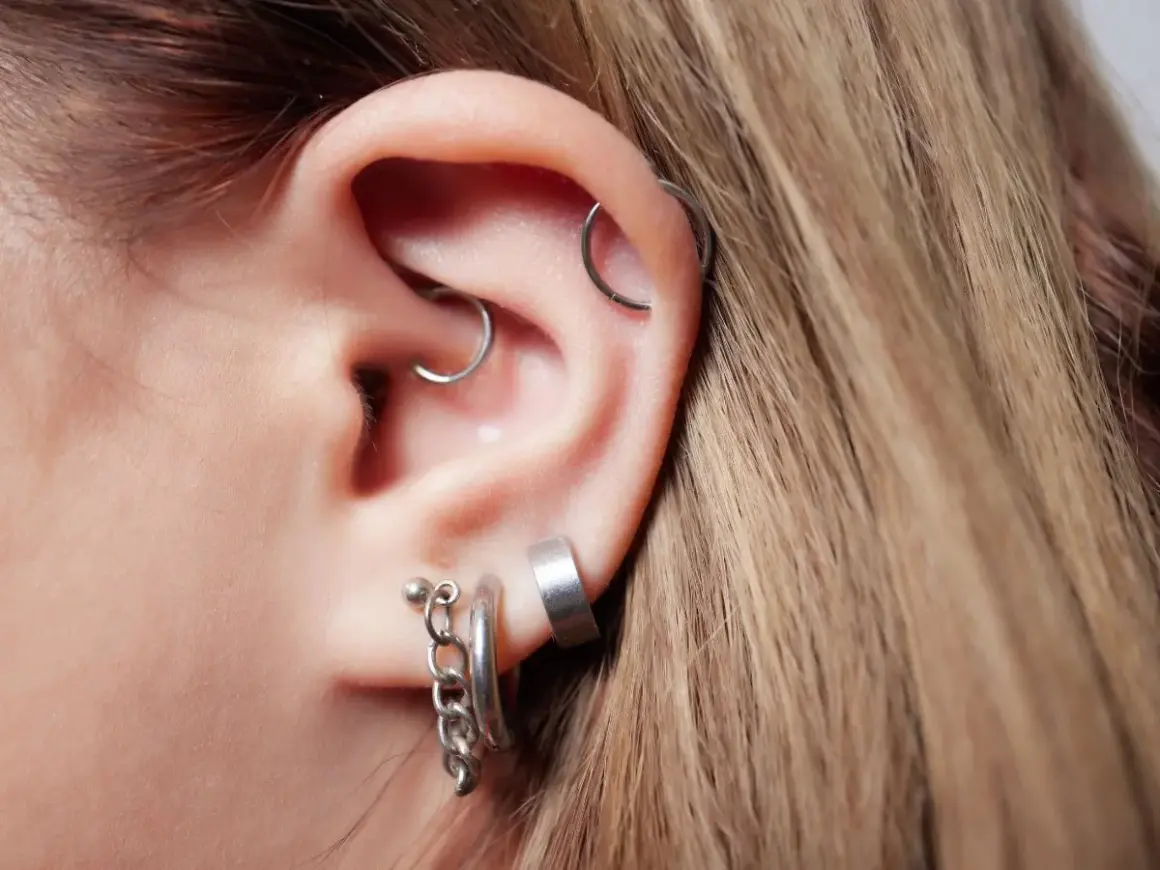 Ucho z kilkoma kolczykami, w tym modnym daith piercingiem.
