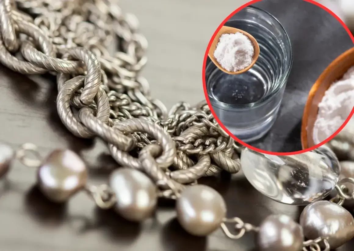Srebrny naszyjnik i perły czekają na czyszczenie biżuterii. W szklance woda, na łyżeczce soda oczyszczona – domowy sposób na blask.