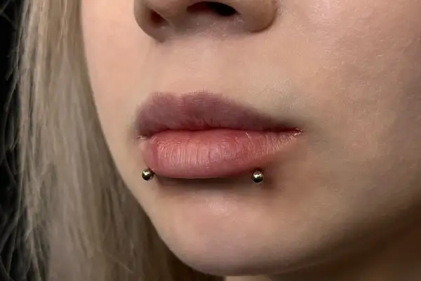 Usta z piercingiem snake bite. Dwa kolczyki z kulkami po bokach dolnej wargi, imitujące ukąszenie węża.
