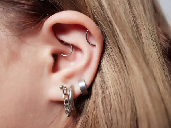 Ucho z kilkoma kolczykami, w tym modnym daith piercingiem.
