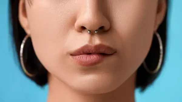 Kobieta z kolczykiem w nosie septum i kolczykami w uszach.