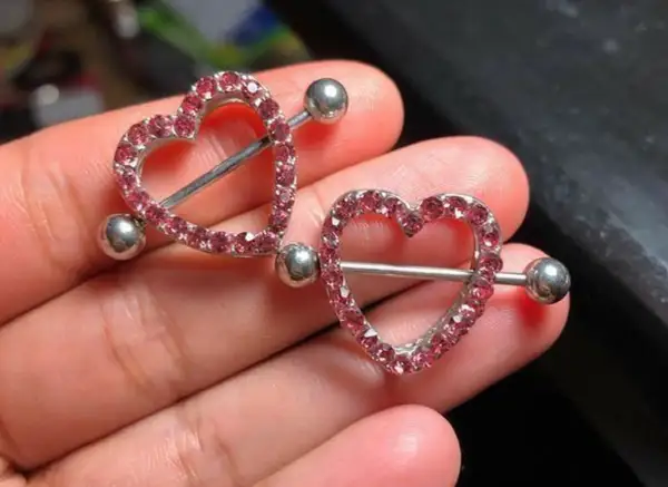 Dwa błyszczące kolczyki w kształcie serca z różowymi cyrkoniami, idealne na nipple piercing.